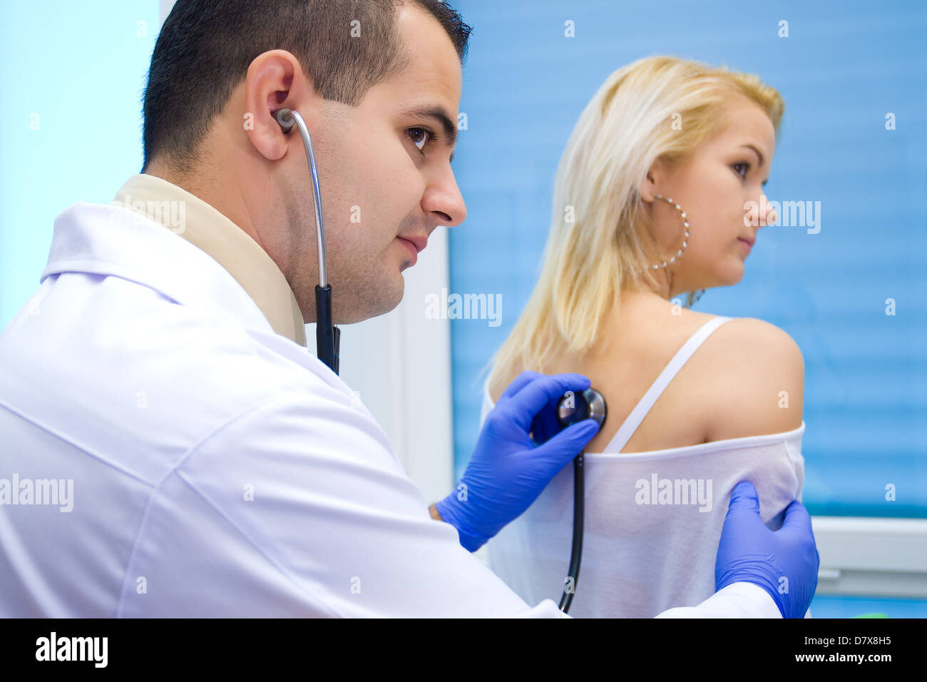 Giovane medico ascolta paziente, uno stetoscopio Foto Stock