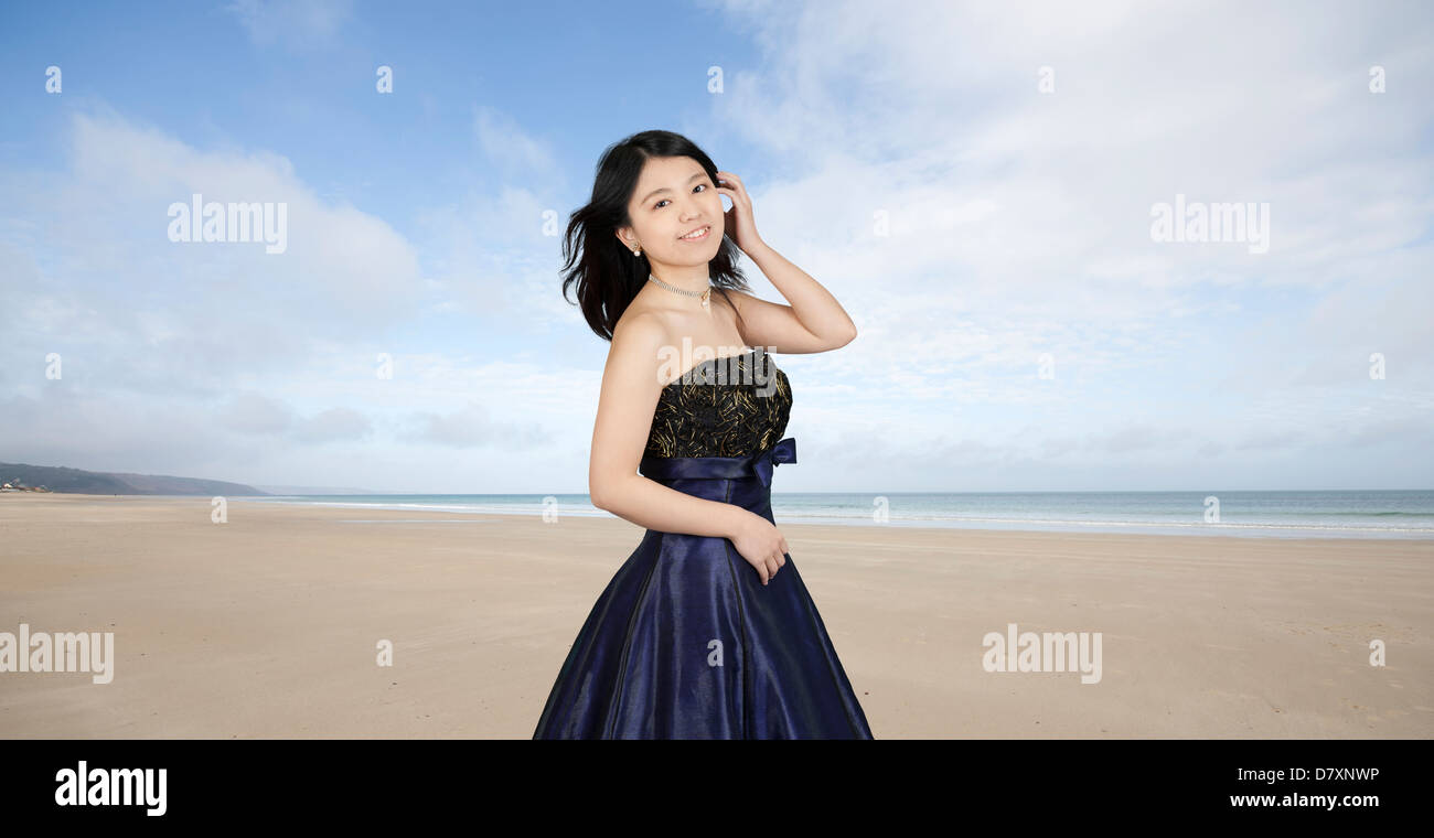 Giovane donna asiatica in abito da sera in spiaggia Foto Stock