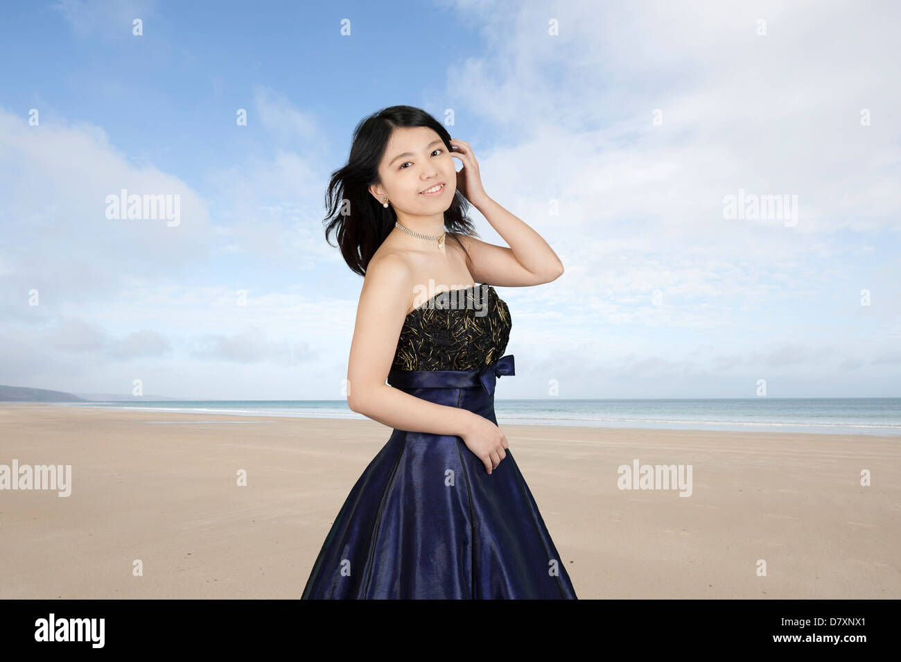 Giovane donna asiatica in abito da sera in spiaggia Foto Stock