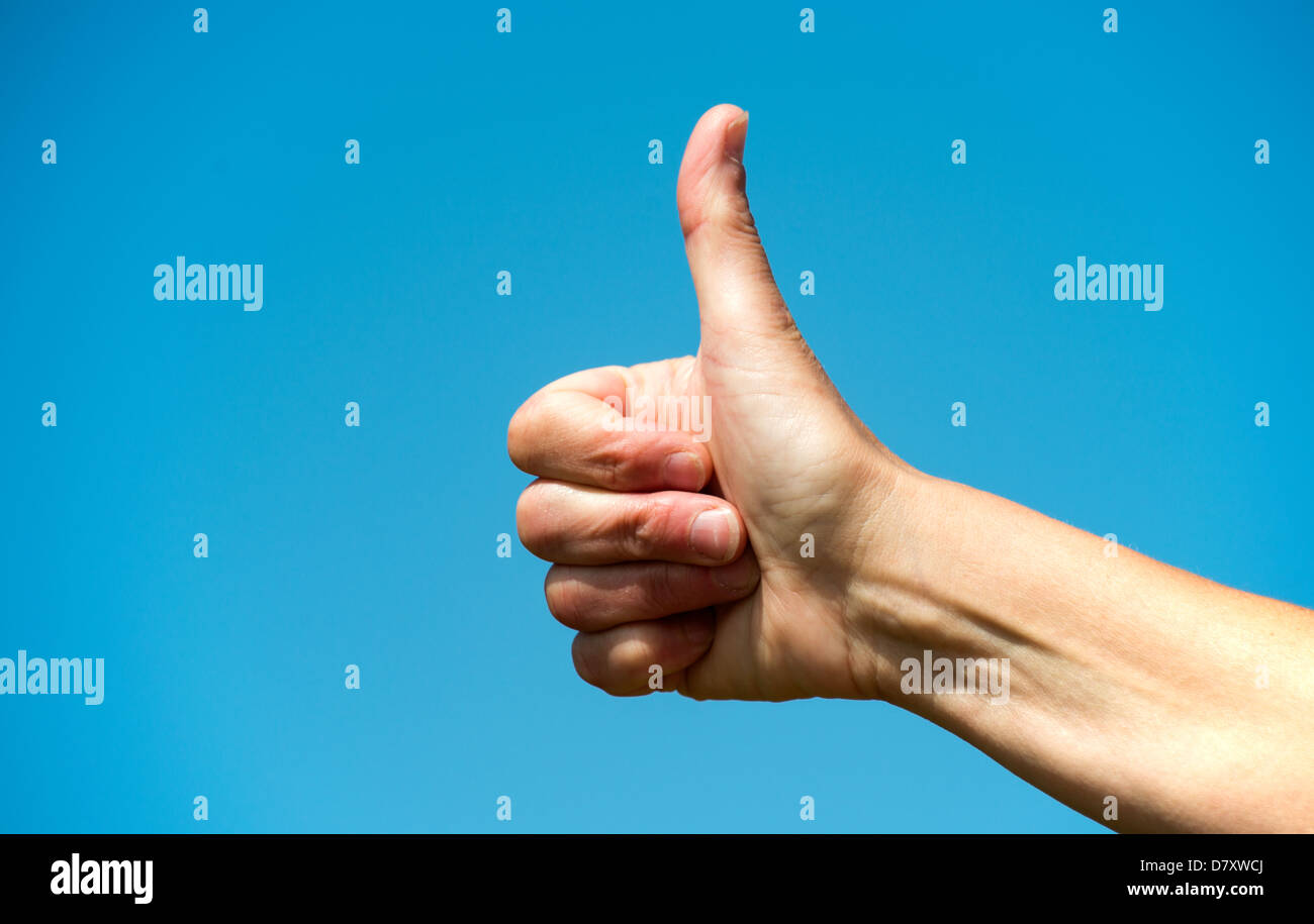 Mano femminile con il pollice in alto sul cielo blu Foto Stock