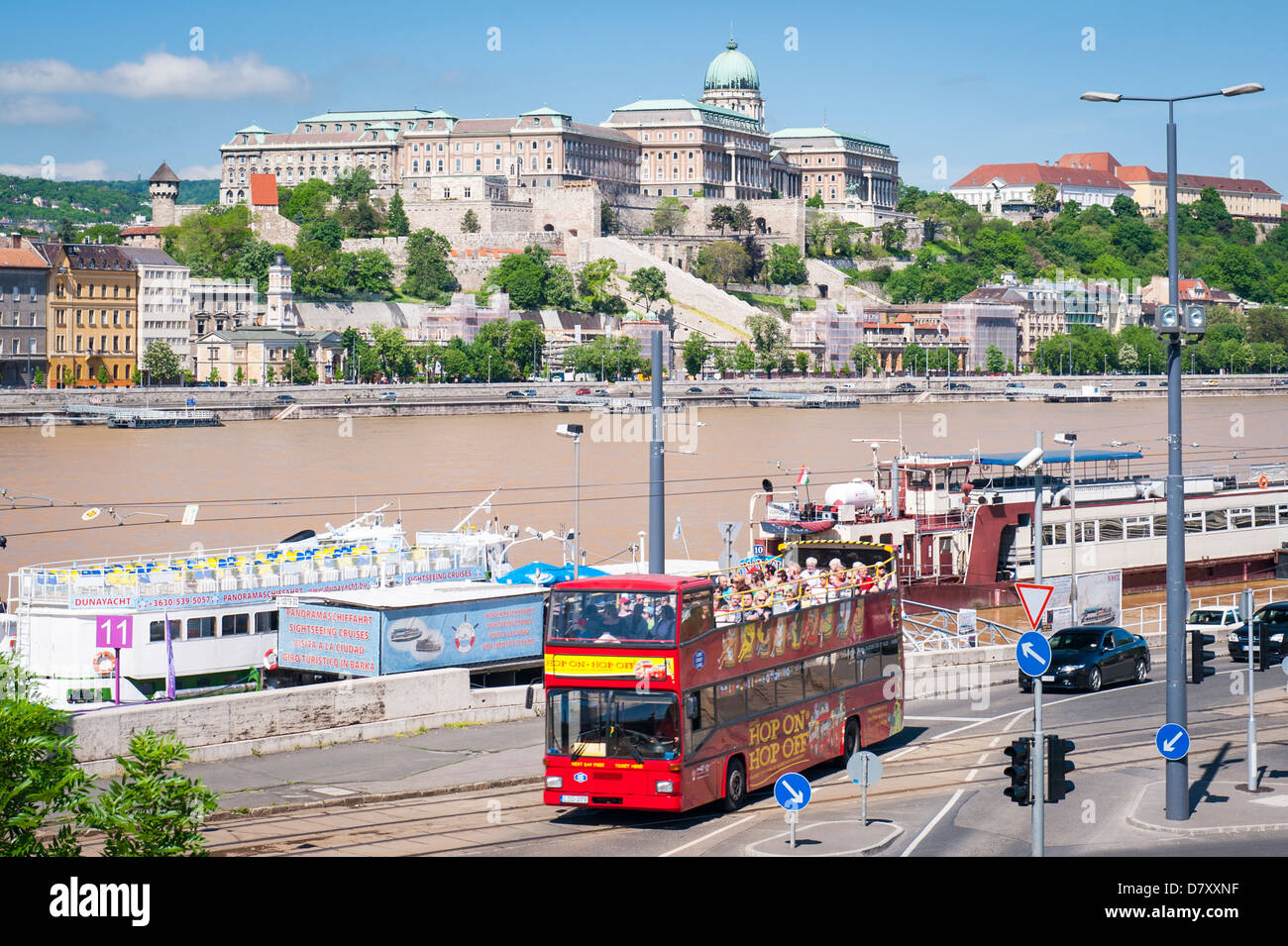 Budapest Ungheria Il Palazzo Reale oltre il Fiume Danubio dal terrapieno di Pest Hop on Hop off bus rosso da imbarcazioni da diporto barca Foto Stock