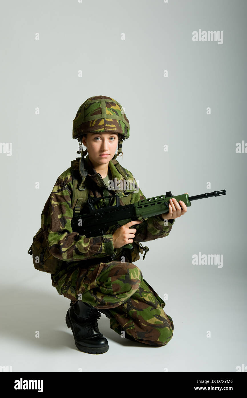 Soldato femmina indossando militare britannico uniforme di mimetizzazione e trattenere un SA80 fucile. Studio shot con uno sfondo semplice. Foto Stock