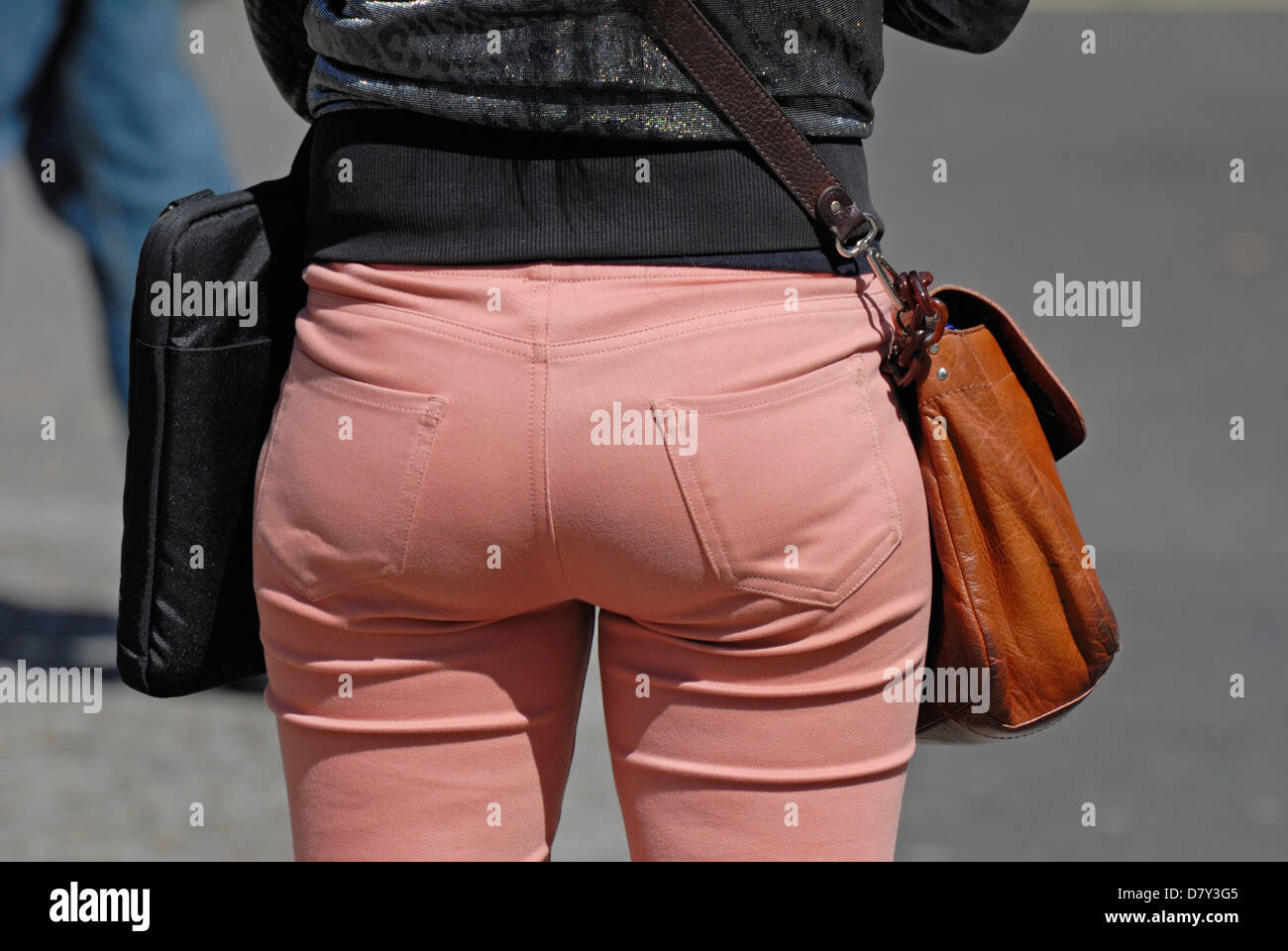 Londra, Inghilterra, Regno Unito. Donna che indossa stretti, rosa, indebolita di jeans e trasporto borsa in pelle Foto Stock