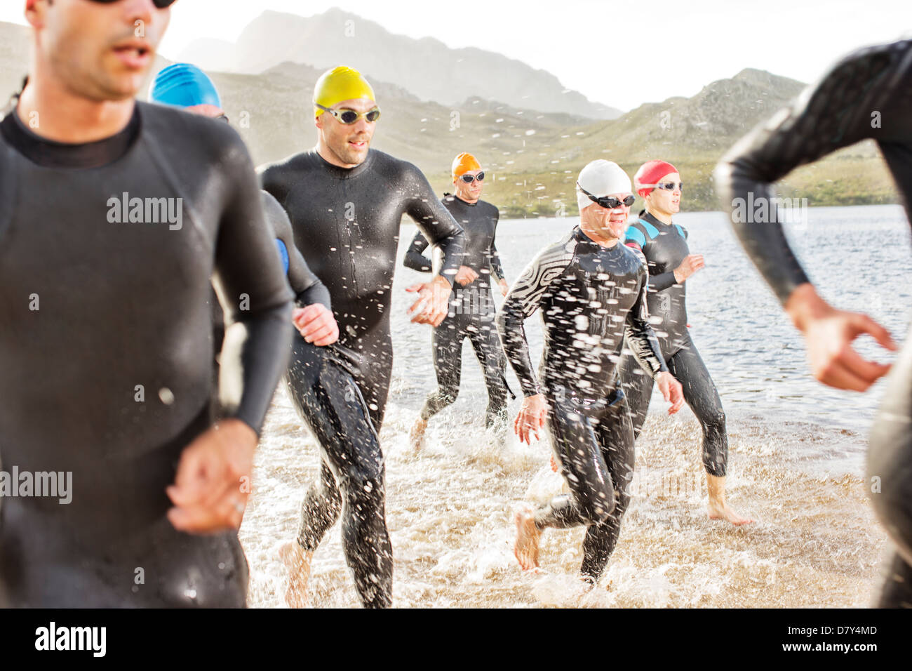 Triatleti in neoprene a piedi in onde Foto Stock