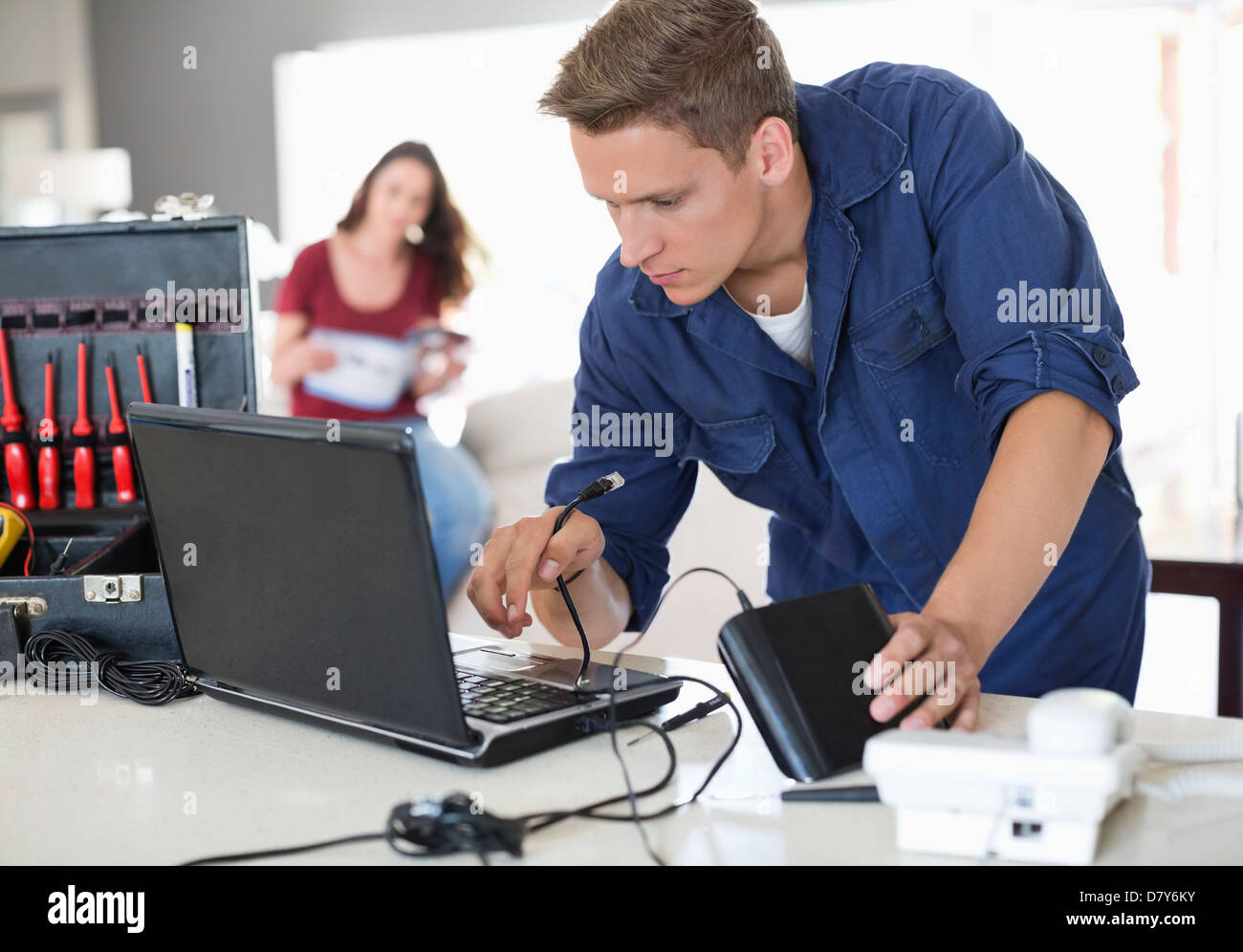 Elettricista utilizzando laptop in casa Foto Stock