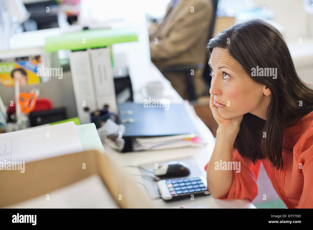 Imprenditrice in appoggio mento in mano sulla scrivania Foto Stock