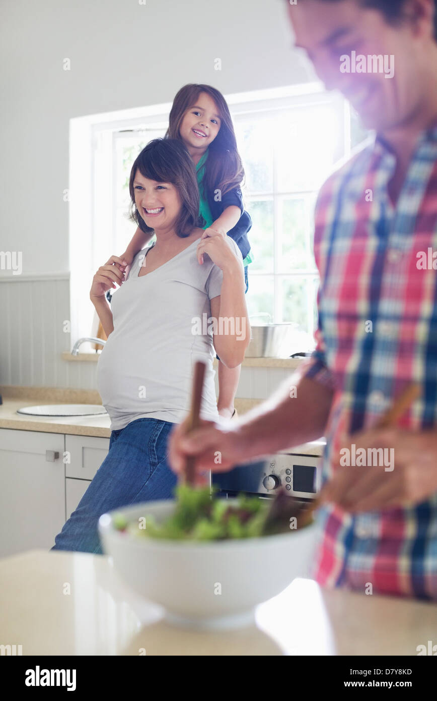 Gravidanza madre e figlia che guarda il padre condire insalate Foto Stock