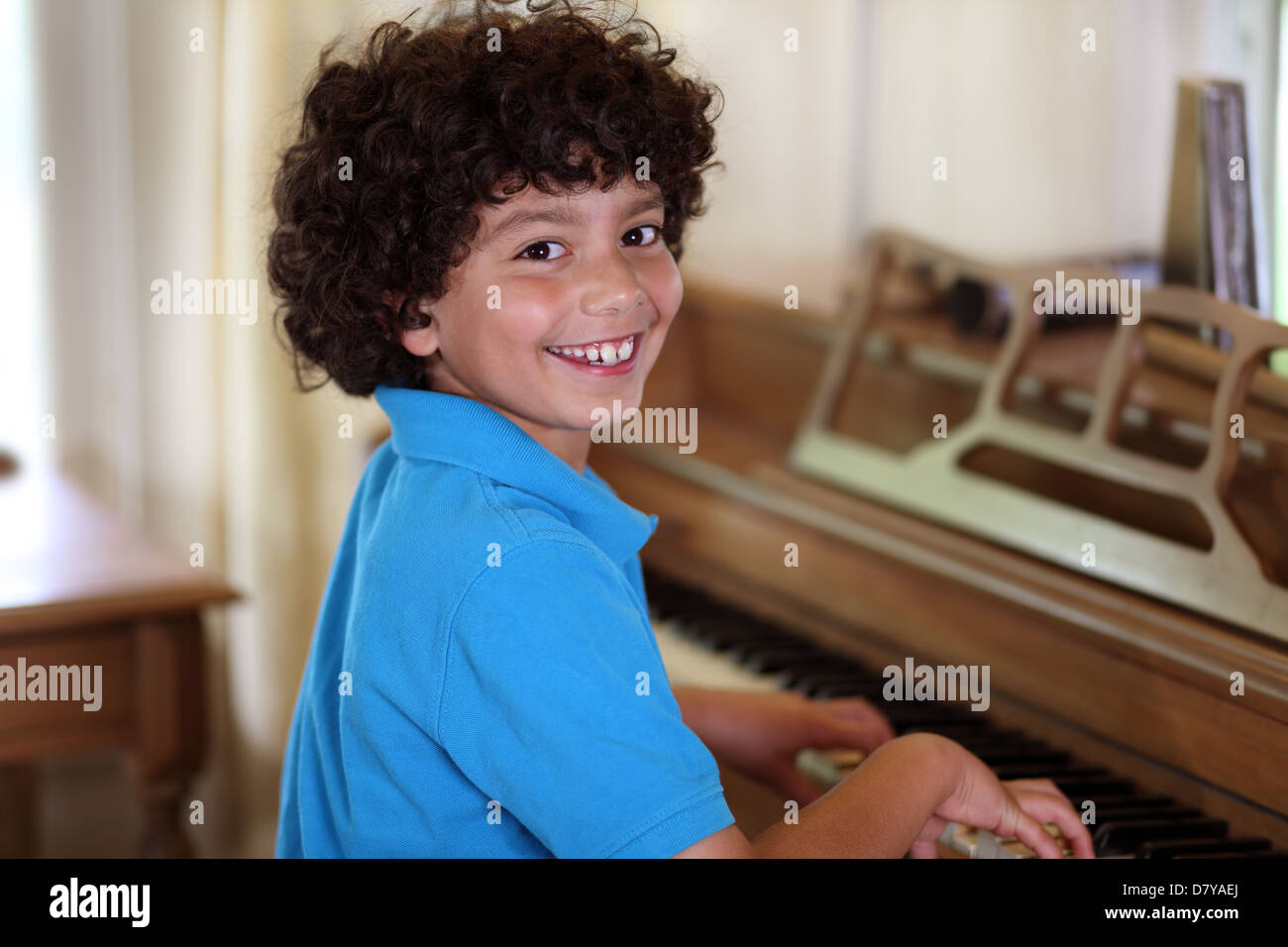 Giovani razza mista boy sorrisi mentre suonare il pianoforte Foto Stock