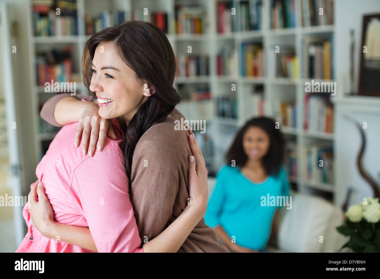 Donne abbracciando in salotto Foto Stock