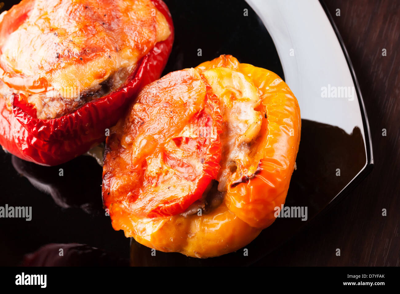 Peperoni ripieni con carne tritata, formaggio e pomodoro su piastra nera Foto Stock