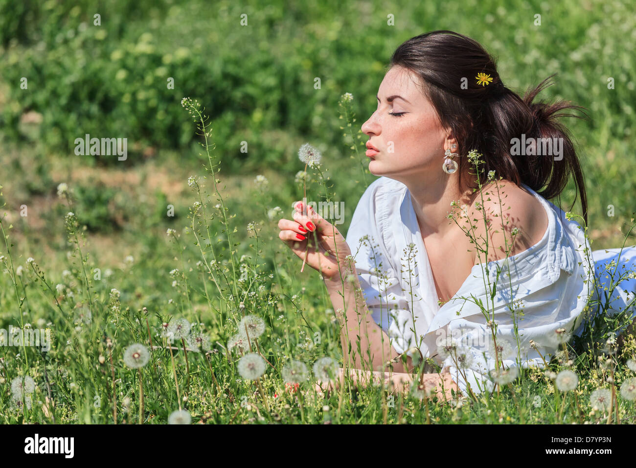 Ragazza con tarassaco giacente su erba verde Foto Stock