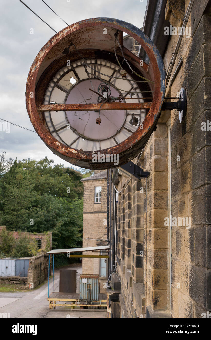 Close-up di grandi rotte orologio arrugginito fissata alla parete in corrispondenza Greenholme Mills, parzialmente abbandonati in lana pettinata vittoriano mill - vicino a Ilkley, nello Yorkshire, Inghilterra. Foto Stock