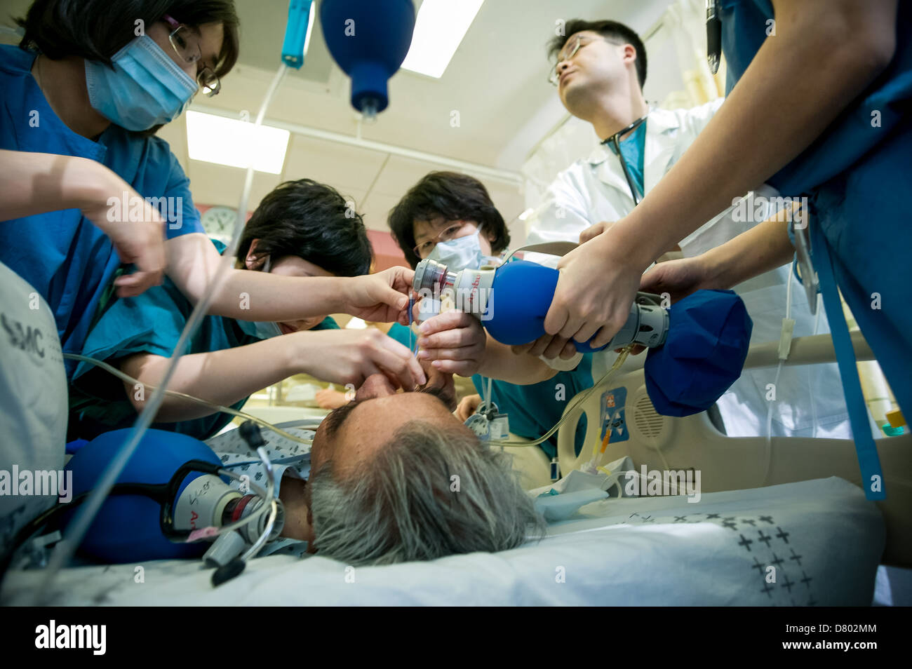 Il personale medico utilizzare un serbatoio di ossigeno per aiutare ravvivare il paziente che è stato sotto anestesia presso l'unità di terapia intensiva Foto Stock
