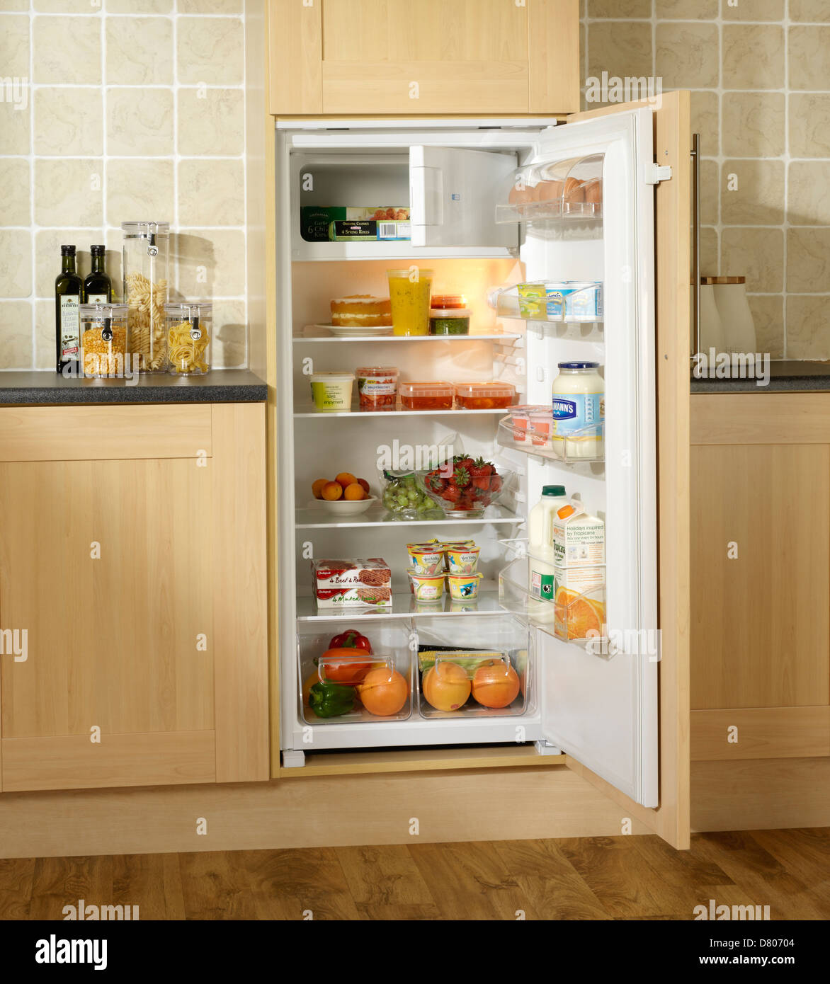 Alimenti refrigerati in una costruito nel frigo con piccolo reparto congelatore in rovere mobili da cucina Foto Stock