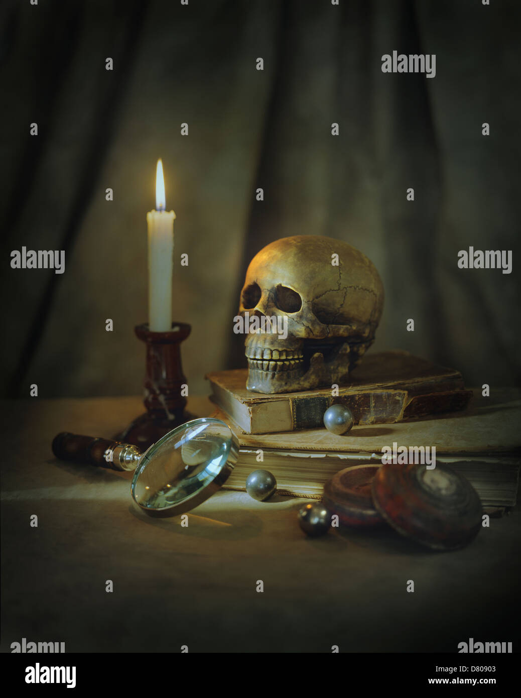 Cranio, lente di ingrandimento, candela ed i libri sul tavolo Foto Stock