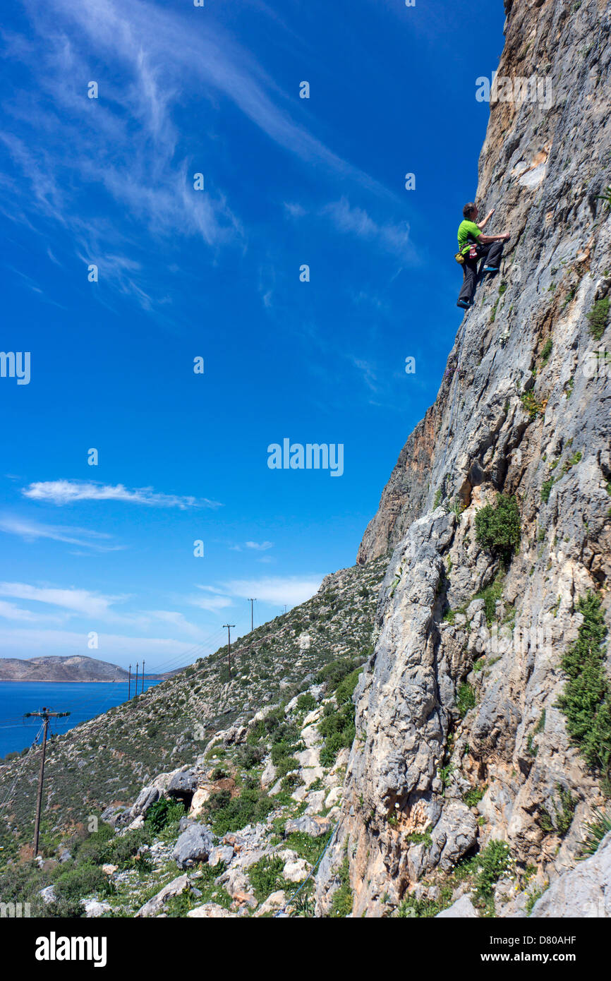 Maschio di rocciatore in verde, rock climbing, Kalymnos Grecia, blu cielo estate Foto Stock