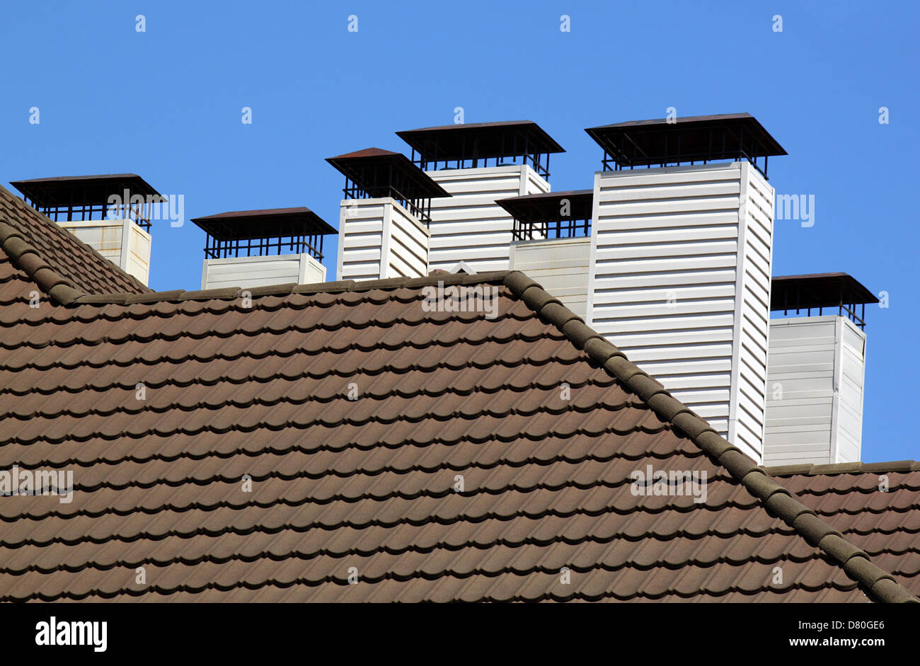 Camini sul tetto di tegole oltre il cielo blu Foto Stock