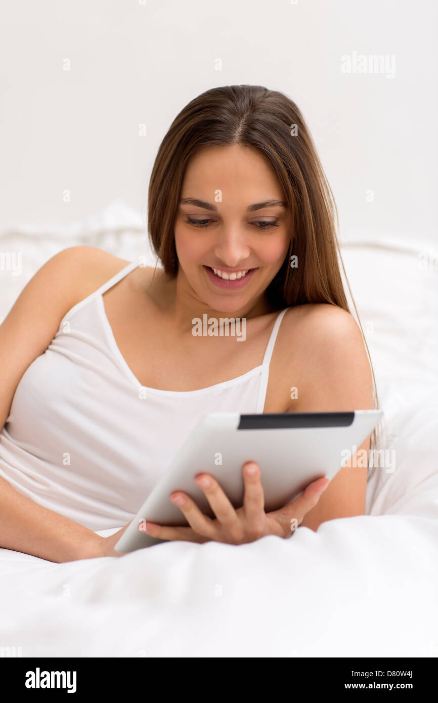Naturale di giovane donna navigare su internet con il tablet pc in camera da letto Foto Stock
