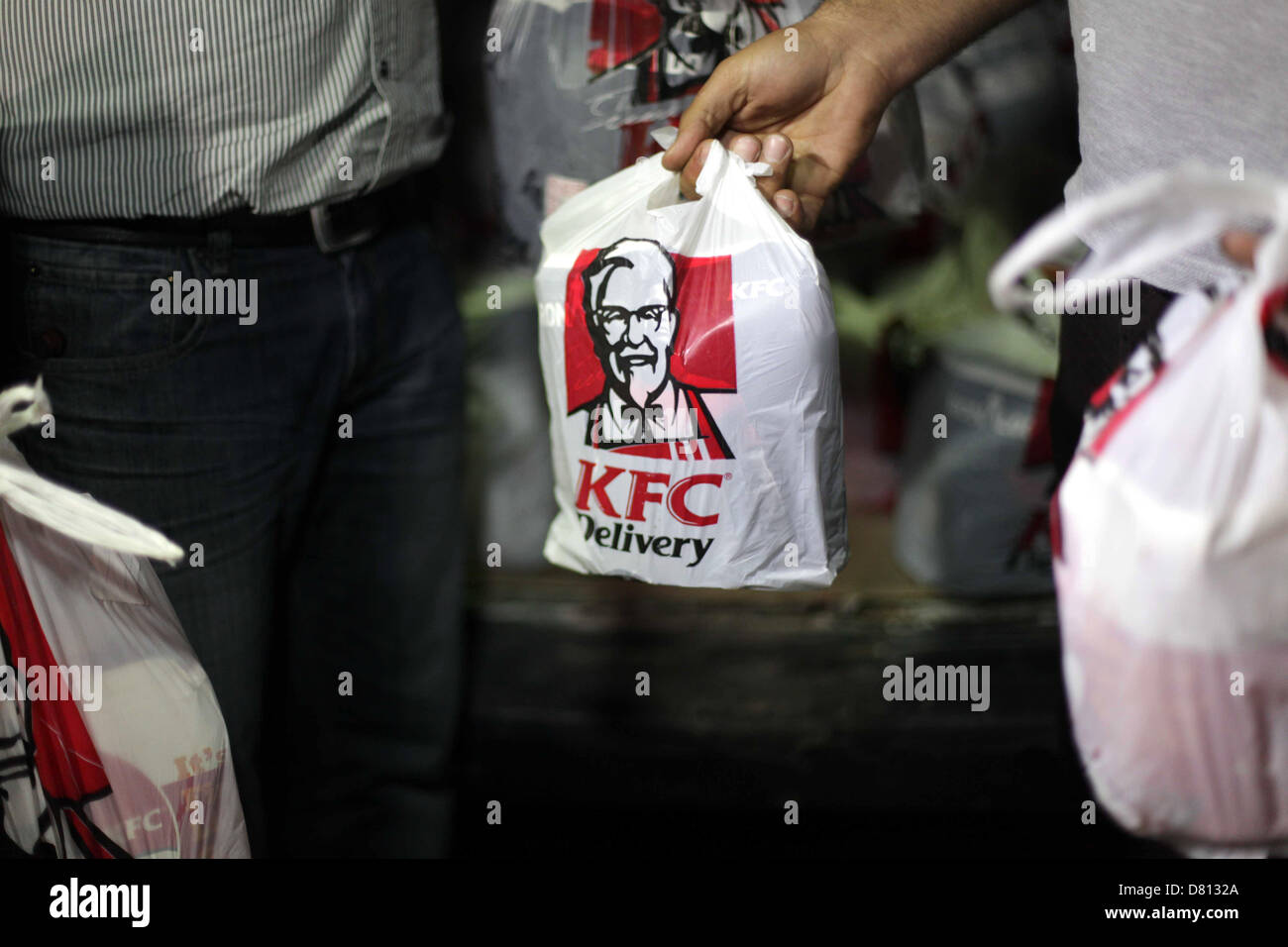 16 maggio 2013 - Gaza City, nella Striscia di Gaza, Territori palestinesi - Consegna dipendenti borse per il trasporto del cibo dal Kentucky Fried Chicken dopo essere arrivati nella città di Gaza attraverso un tunnel sotterraneo che collega la striscia di Gaza per l'Egitto, il 16 maggio 2013. Il fast food è solo l'ultima tendenza di contrabbandieri che cercano di girare un buck portando in hard-to-Ottieni prodotti per la Striscia di Gaza, che è stato al di sotto di un blocco israeliano dal 2007. Non si tratta esattamente di '"fast" -- prendendo diverse ore per arrivare, con la parte palestinese società di consegna dietro di esso carica prezzi hefty per coprire il costo del carburante e dei trasporti (credito Im Foto Stock