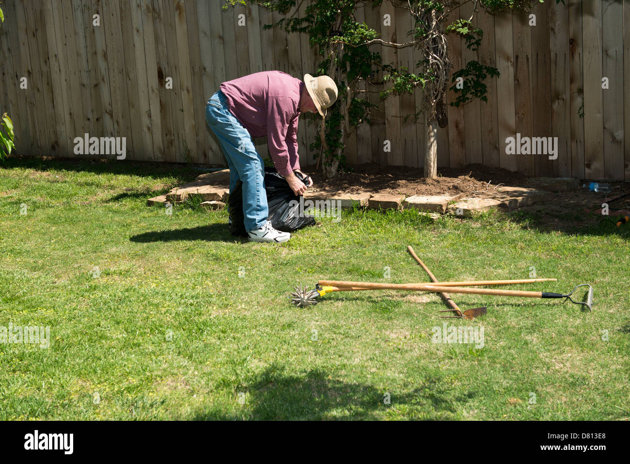 Un 75 enne senior uomo caucasico esegue lavori di giardinaggio nella sua casa. Oklahoma, Stati Uniti d'America. Foto Stock
