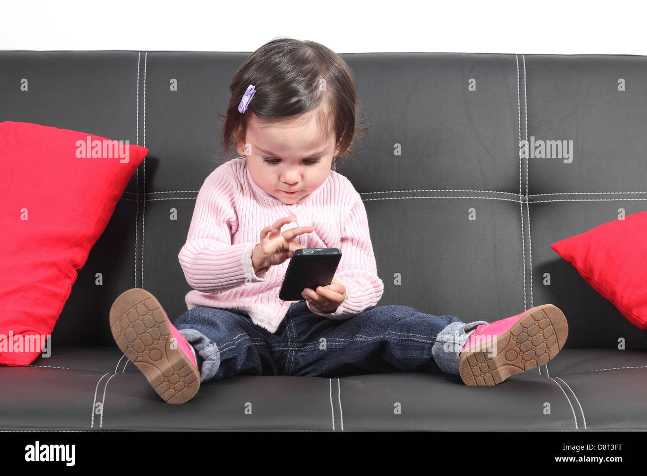 Casual baby sitter su un lettino a casa la riproduzione e toccare un telefono mobile Foto Stock