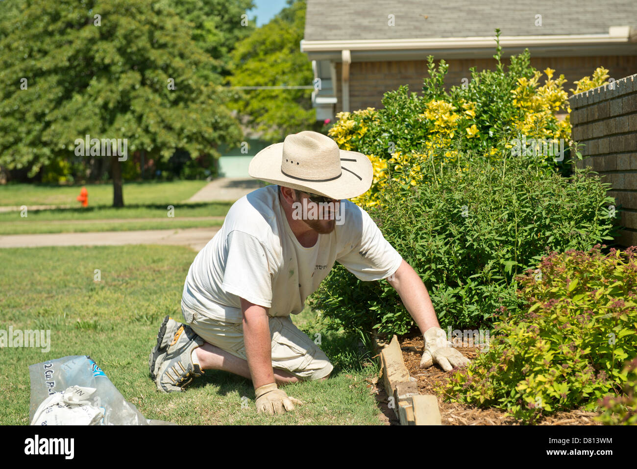 Un uomo caucasico, 27 anni, la pacciamatura si diffonde in un letto contenente arbusti. Oklahoma, Stati Uniti d'America. Foto Stock