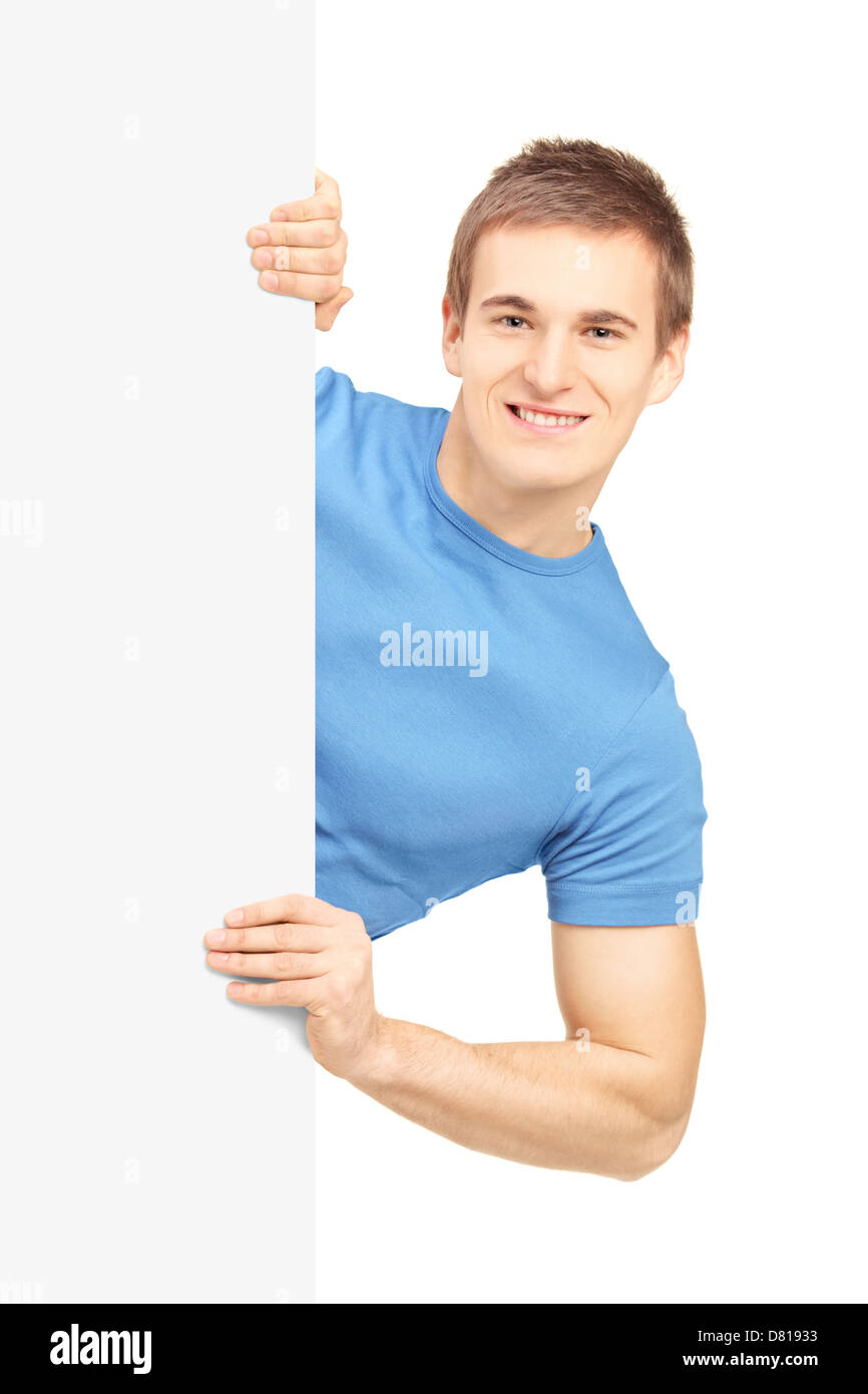 Casual giovane uomo in posa dietro il pannello bianco, isolato su sfondo bianco Foto Stock