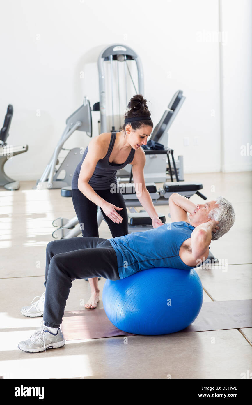 Vecchio uomo ispanico lavora con trainer in palestra Foto Stock