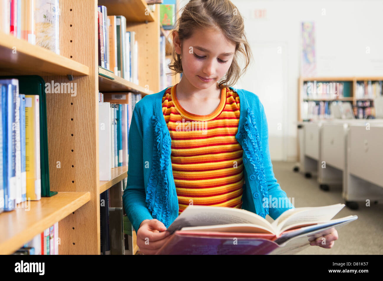 Ragazza caucasica la lettura di libro in biblioteca Foto Stock