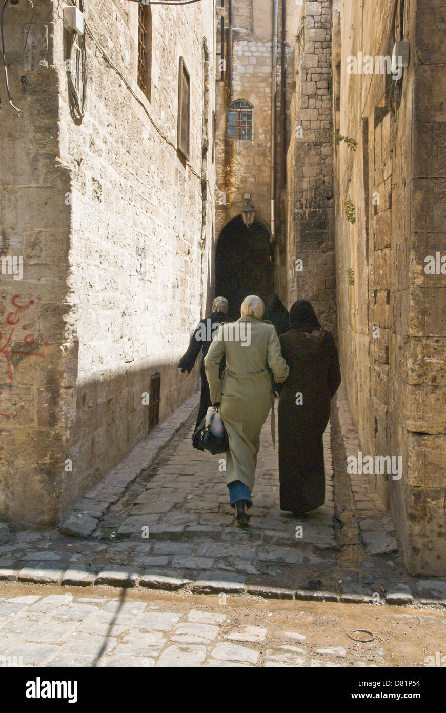 Aleppo, Siria. Le donne a piedi verso il basso un vecchio stretta strada di ciottoli nel centro della città vecchia, un sito Patrimonio Mondiale dell'UNESCO. Foto Stock