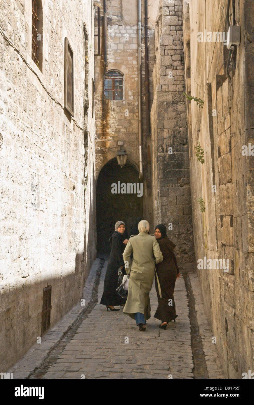 Aleppo, Siria. Le donne a piedi verso il basso una stretta vecchia strada di ciottoli nel centro della città vecchia, un sito Patrimonio Mondiale dell'UNESCO. Foto Stock