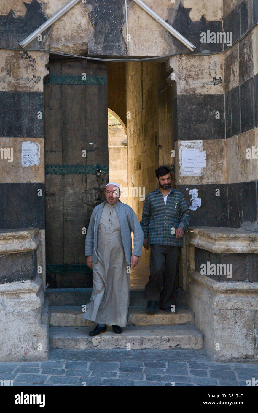 Aleppo, Siria. Gli uomini in uscita all'ingresso di una vecchia moschea nel centro della città vecchia Foto Stock