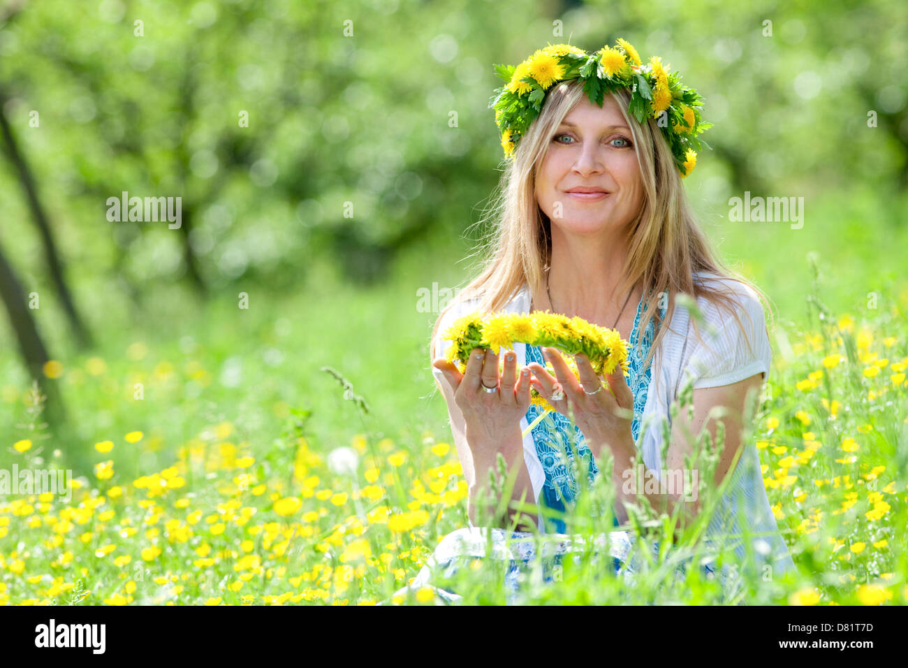 Donna con la ghirlanda di fiori ubicazione in un prato di primavera Foto Stock