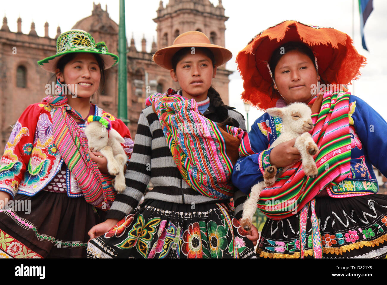 Ragazze in abito tradizionale tenendo un agnellino. Plaza de Armas, Cuzco, Perù Foto Stock