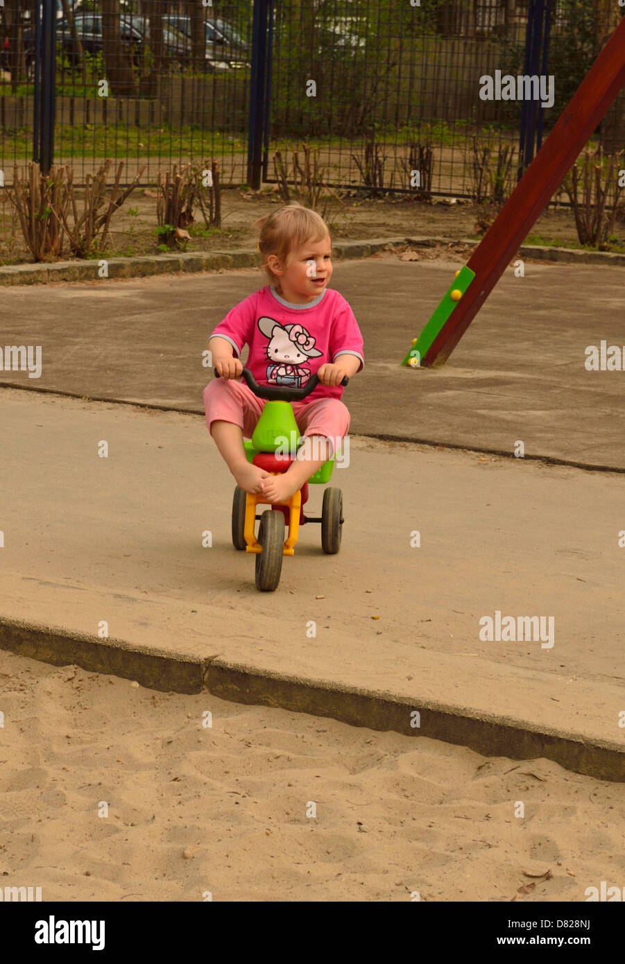 2 anno di età bambina sul triciclo sul parco giochi Foto Stock