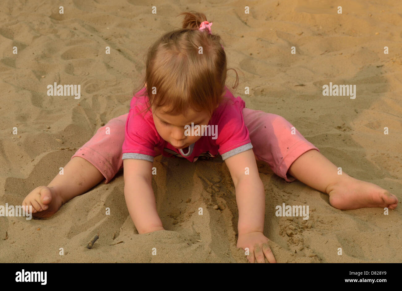 2 anno di età bambina giocando in sabbia al parco giochi Foto Stock