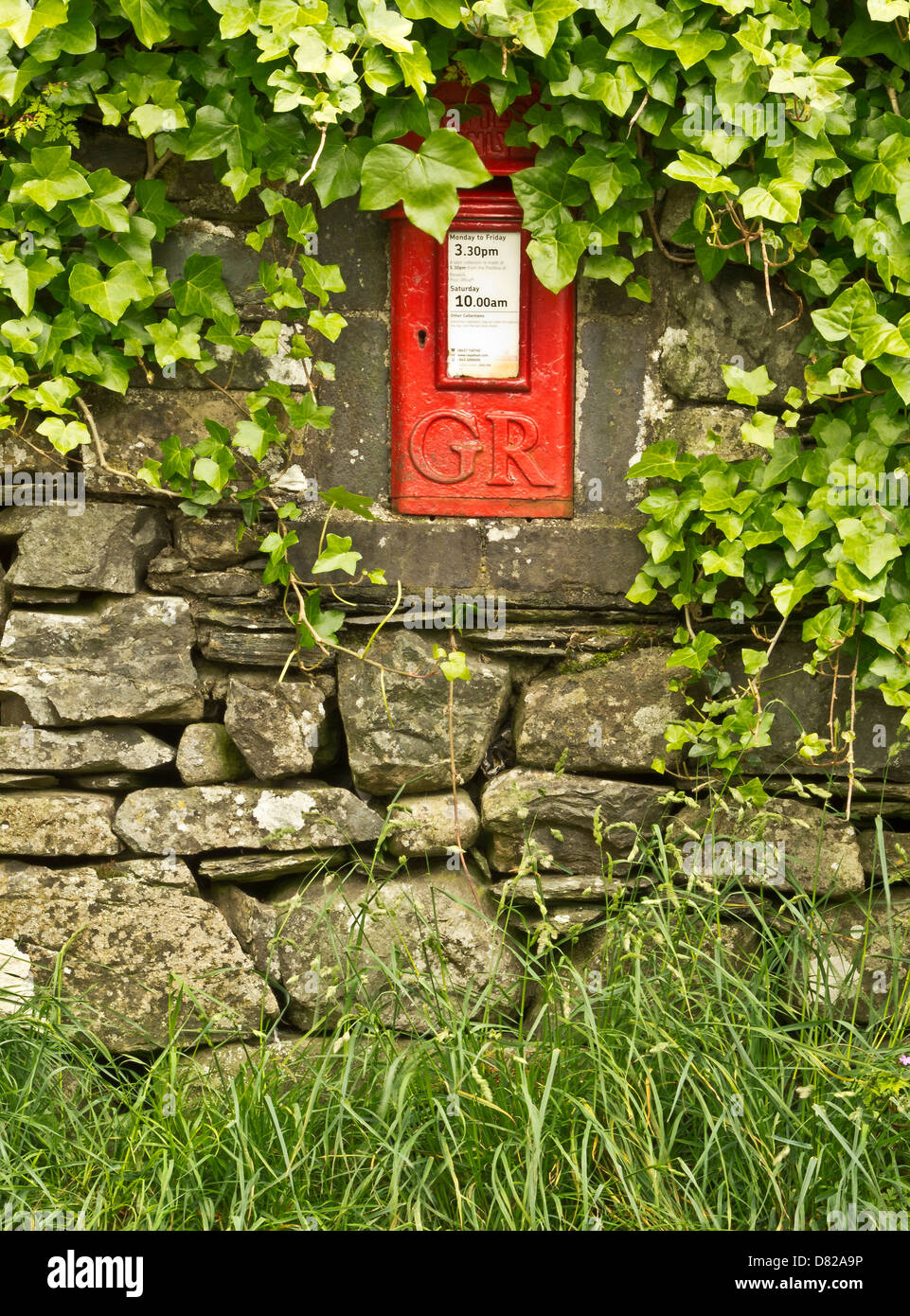 Rosso casella postale all'interno di secco di muro di pietra inn un villaggio a Stonewaite nel Lake District, Cumbria, Regno Unito Foto Stock