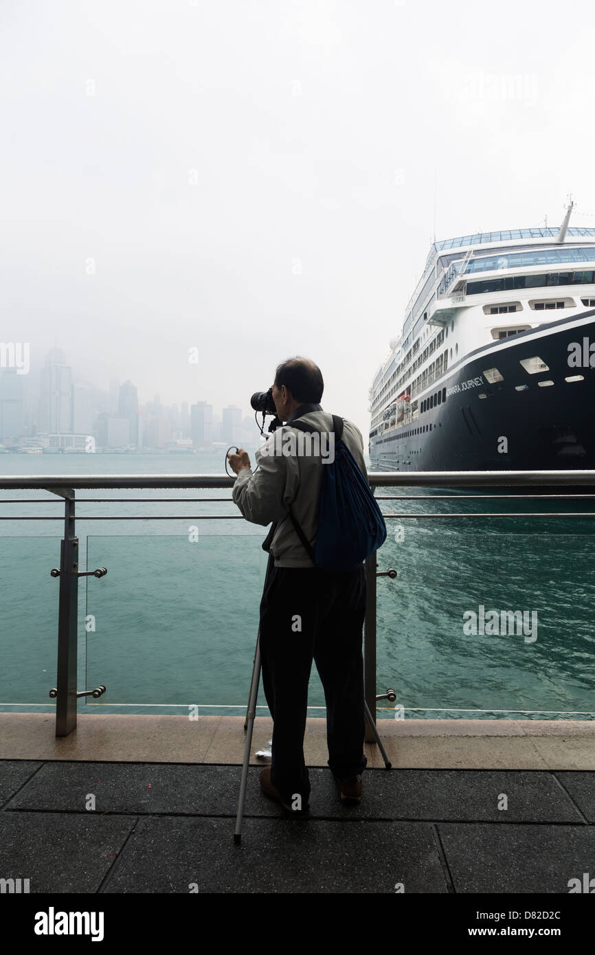Fotografo di scattare le foto della skyline di Hong Kong accanto a una grande nave da crociera Foto Stock