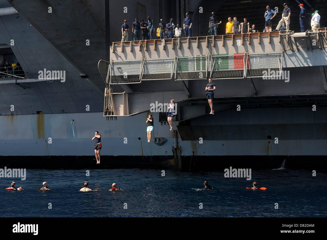 I marinai saltare da un aeromobile ascensore durante una nuotata chiamata. Foto Stock