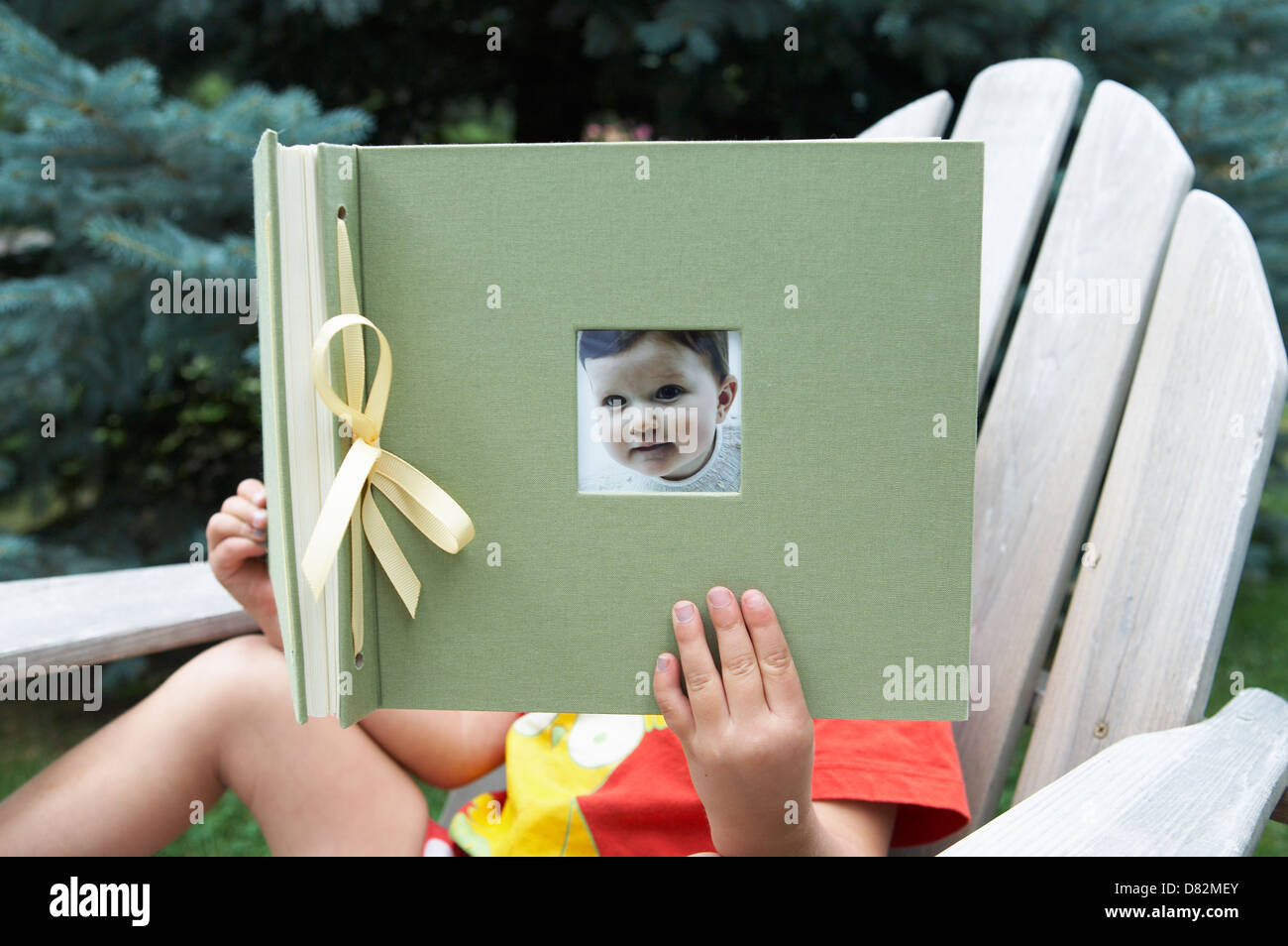 Bambino azienda album di foto con il suo bambino foto sulla parte anteriore Foto Stock