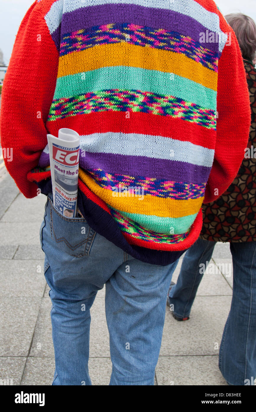 Liverpool, Regno Unito il 17 maggio 2013. Uomo che porta Liverpool Echo con le notizie del liner RMS Queen Mary 2 ormeggiato sulla sua visita alla città. Il Liverpool Cruise Terminal è un 350-metro-lunga struttura galleggiante situato sul fiume Mersey consentendo grandi navi da crociera per visitare senza inserire il dock chiuso o sistema di ormeggio a metà fiume e i passeggeri di gara a terra. Il terminale è stato ufficialmente inaugurato il 21 Settembre 2007 da Sua Altezza Reale il Duca di Kent quando la Queen Elizabeth 2 ormeggiate presso il terminale. Foto Stock
