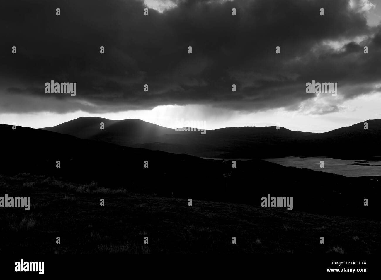 Rainy moody skies con sun inserimenti attraverso le nuvole sulle montagne di dare speranza e di cambiamento per il futuro Foto Stock