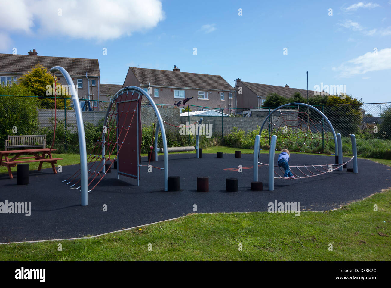 3 anno vecchia ragazza giocando su un corso di arrampicata in un parco giochi della comunità. Foto Stock