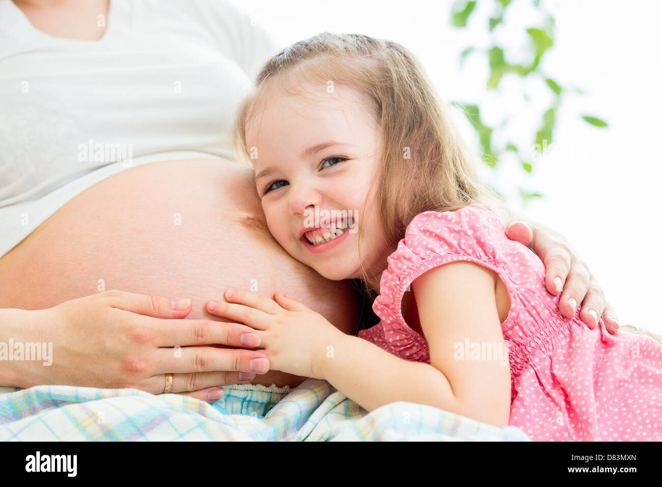 Bambino ragazza ascolto in stato di gravidanza della madre ventre Foto Stock