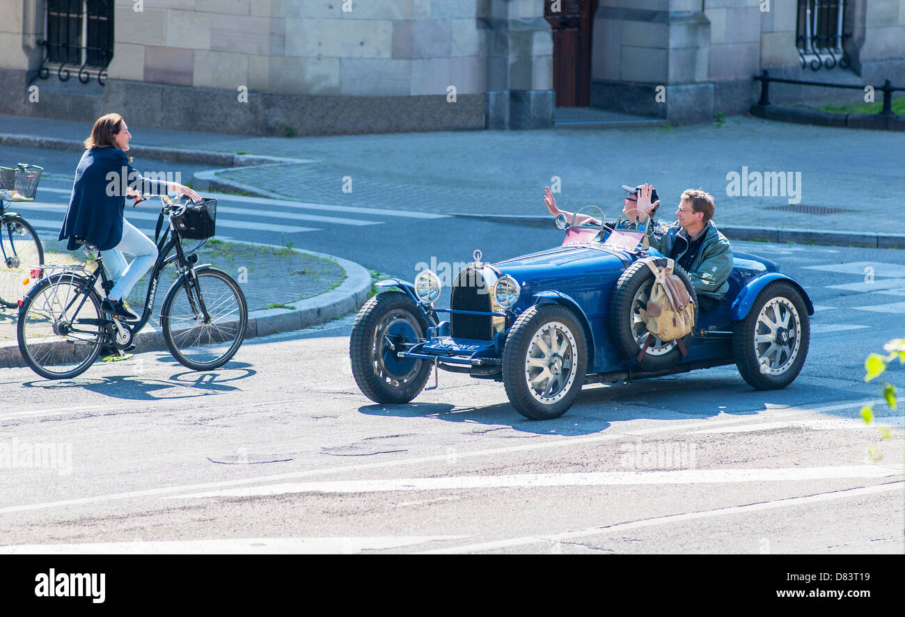 2 uomini alla guida di un blu convertibile Bugatti francese d'epoca che sventola motociclista femminile, salutando, Strasburgo Alsazia Francia Europa Foto Stock