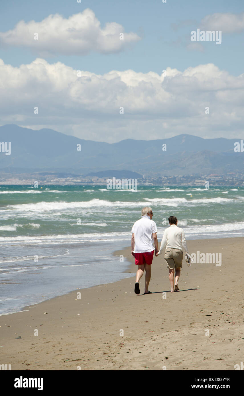 Coppia in pensione tenendo le mani, passeggiate sulla spiaggia di Marbella. Costa del Sol, Spagna. Foto Stock