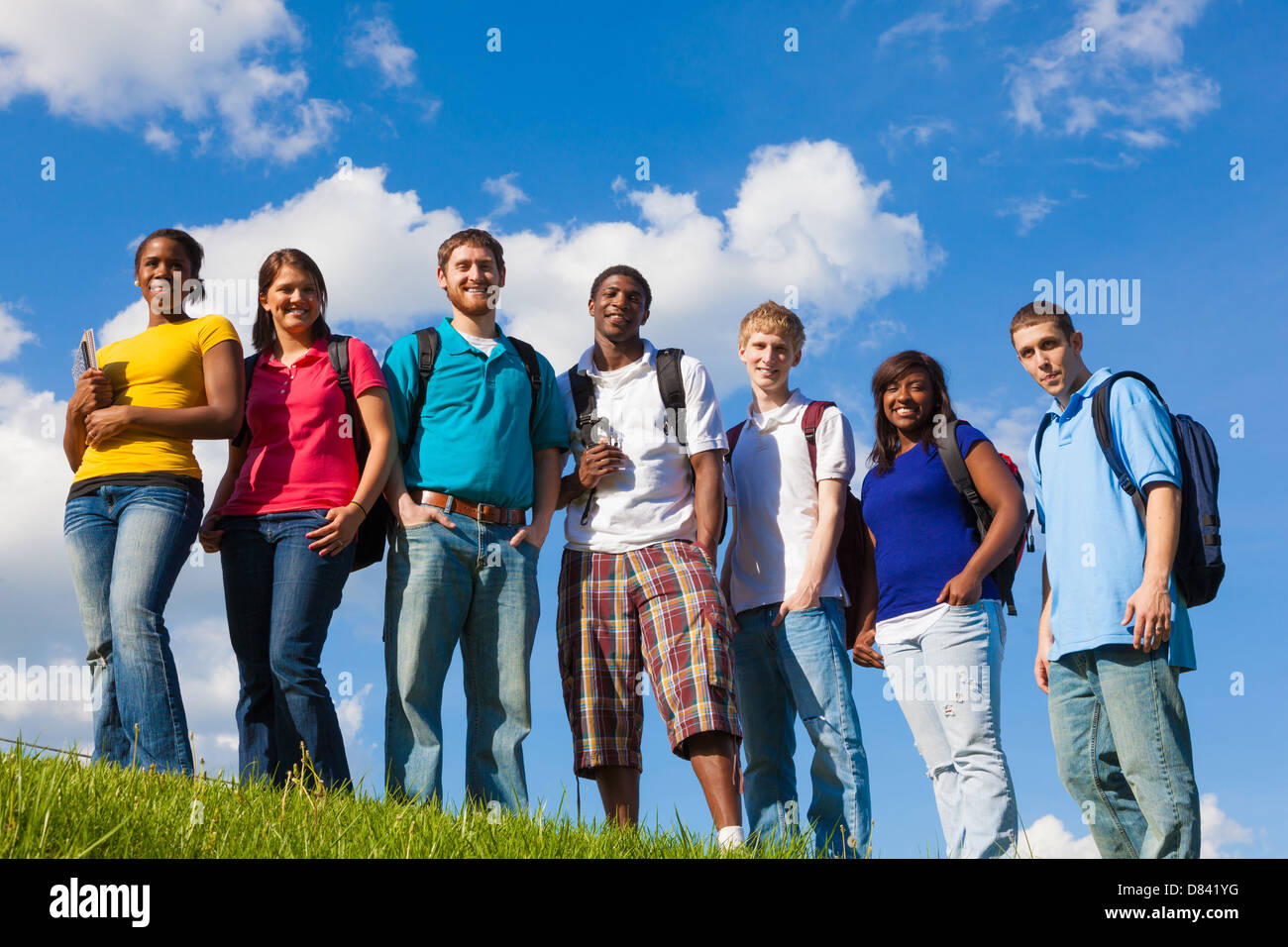 Un gruppo di diversi studenti del college/amici al di fuori su di un colle con un background di sky Foto Stock