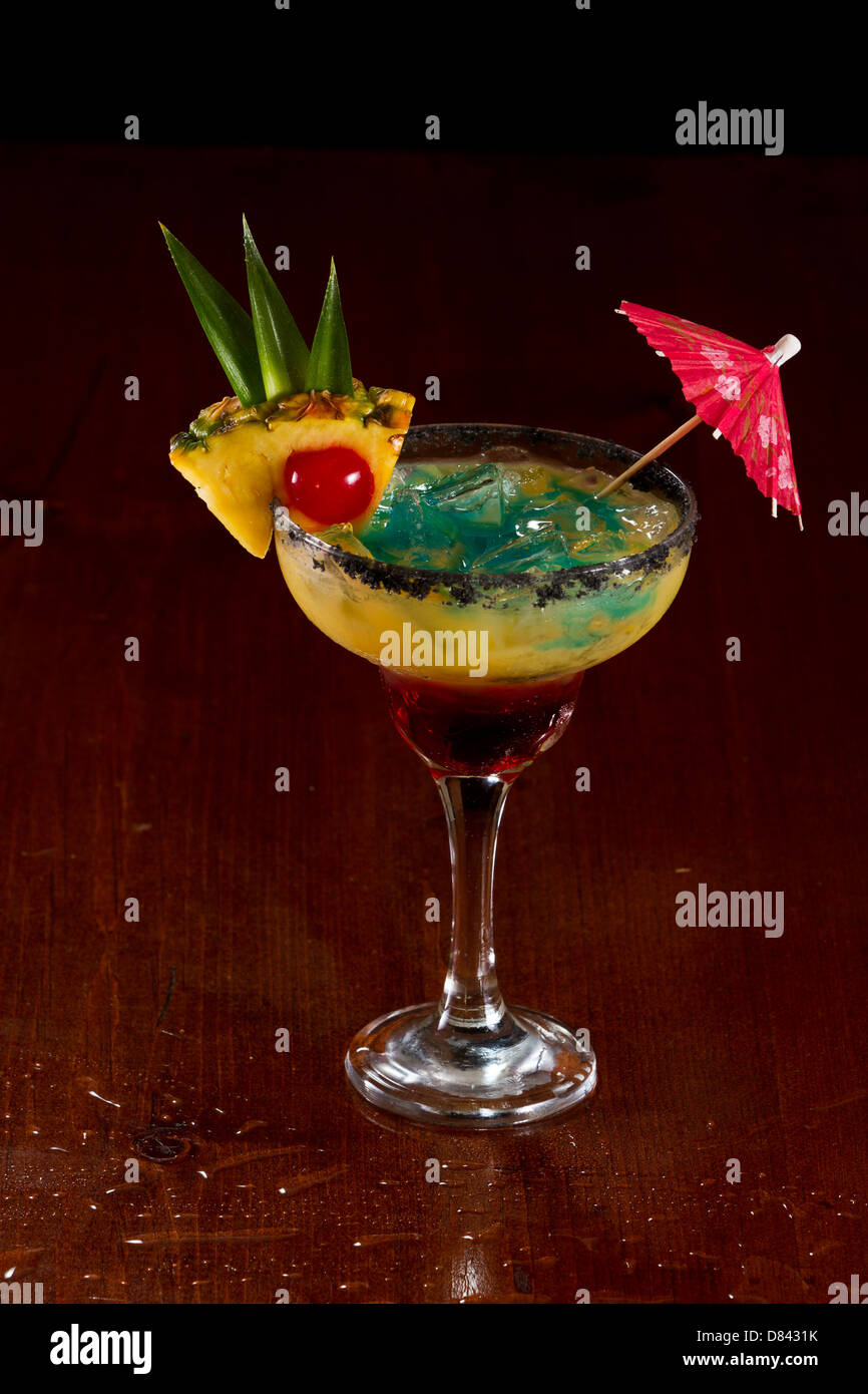 Bella tropical cocktail servito in un bicchiere Margarita con sale nero sul cerchio e una fetta di ananas con una ciliegia in esso Foto Stock