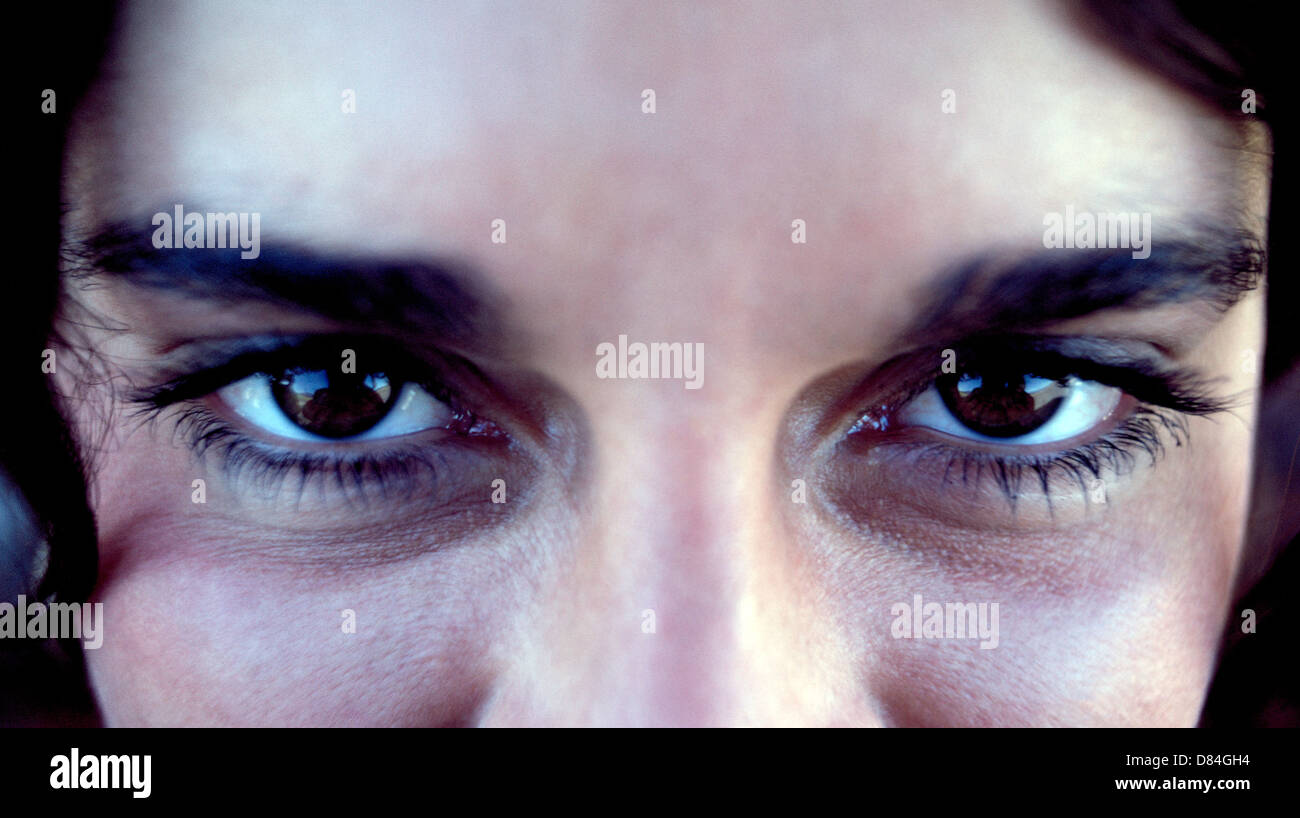 Un extreme close-up della intrigante occhi marroni di un attraente ragazza la ventenne che ha anche le ciglia lunghe e spesse sopracciglia scure. Foto Stock