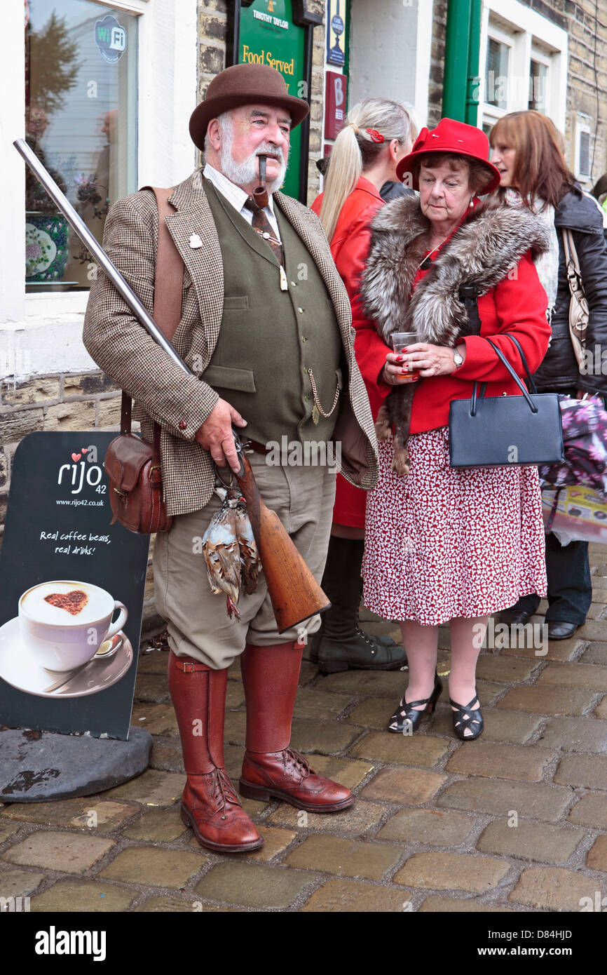 Haworth 40's Weekend Country Gentleman e la moglie con il fucile e selvaggina di penna appeso dal nastro Foto Stock